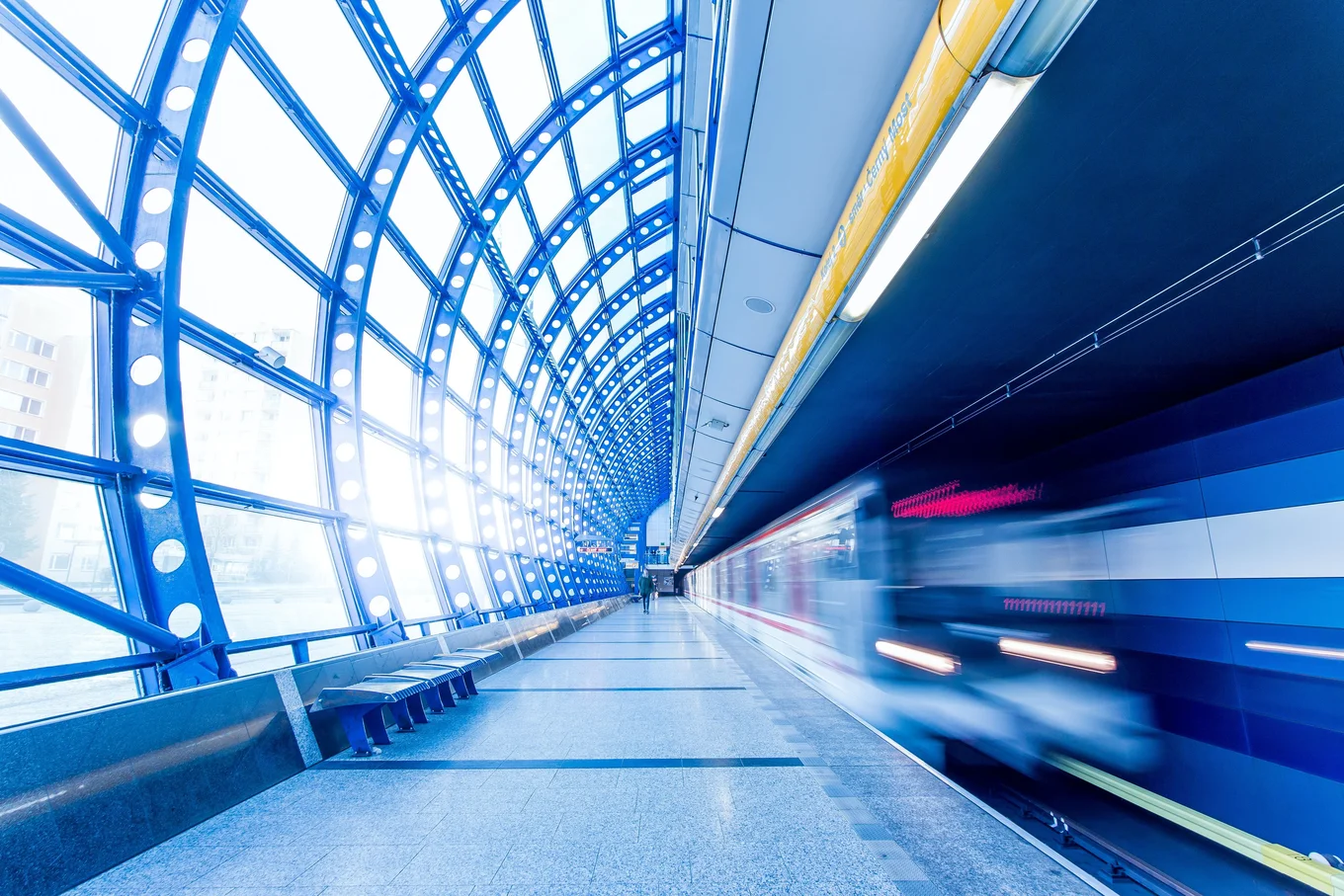 Blue arched tunnel, blurred train, empty platform.